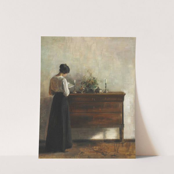 Interiør med kunstnerens hustru, der står ved en kommode og læser by Carl Holsøe