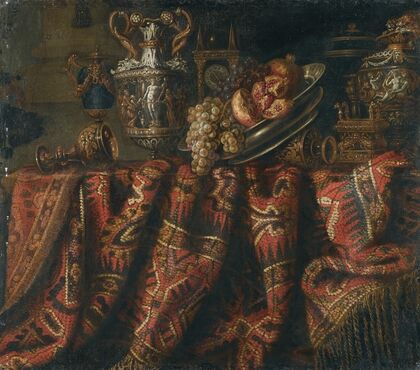 A Still Life With Pomegranates, And Grapes On A Table Draped With An Ornate Turkish Carpet And Assorted Orfèvrerie