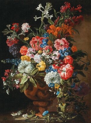 Carnations, lillies, nigellas and other flowers in a decorative terracotta vase on a stone ledge